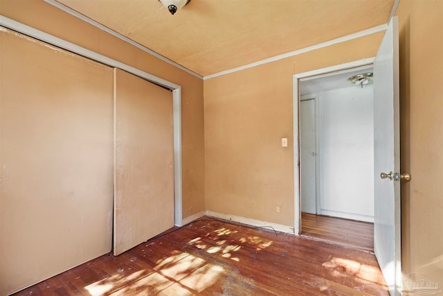 unfurnished bedroom with wood-type flooring, a closet, and ornamental molding