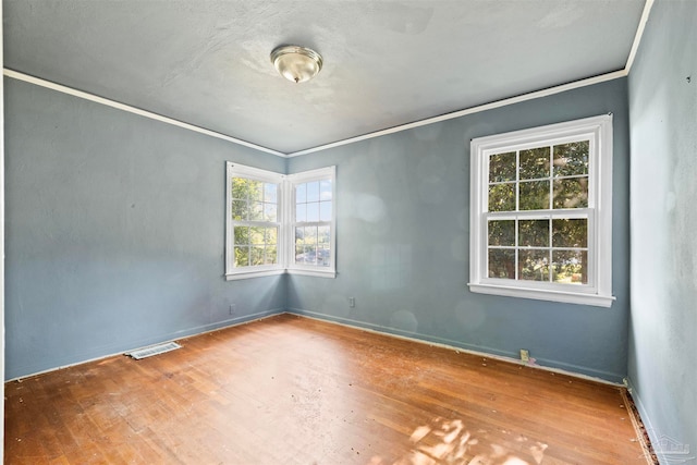 empty room with crown molding, hardwood / wood-style floors, and a healthy amount of sunlight