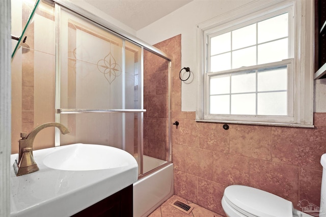 full bathroom with tile patterned flooring, tile walls, shower / bath combination with glass door, and toilet