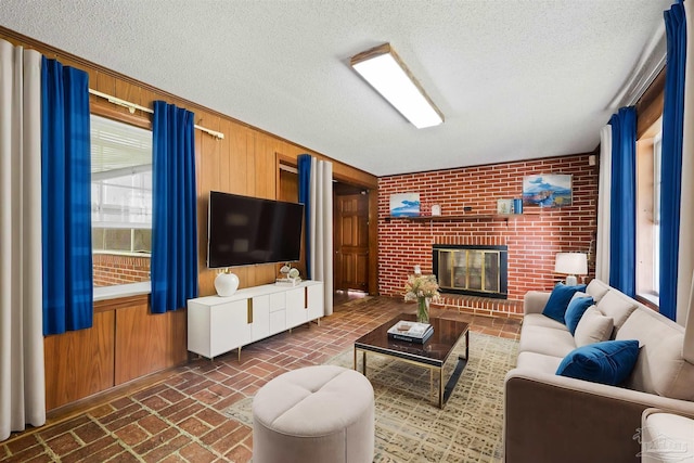 living room featuring a brick fireplace, wood walls, brick wall, and a textured ceiling