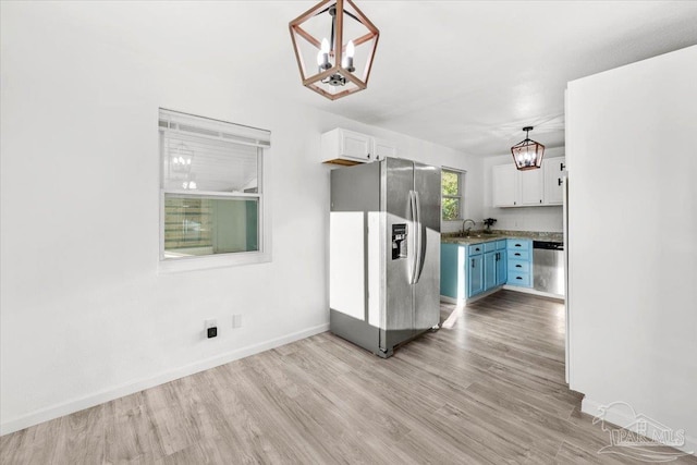 kitchen featuring a sink, white cabinetry, appliances with stainless steel finishes, and an inviting chandelier