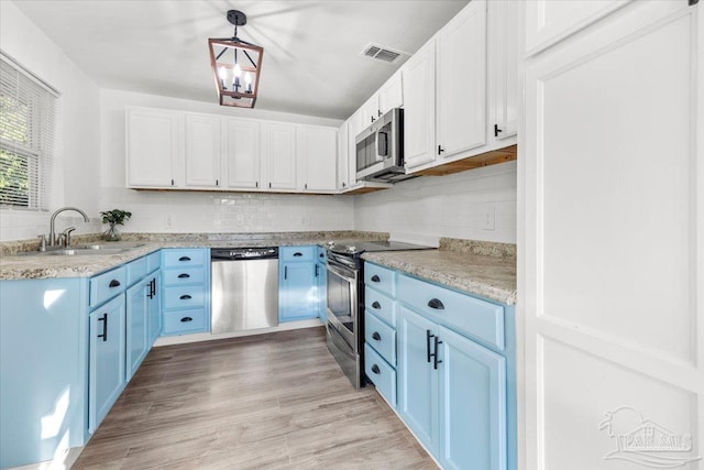 kitchen featuring visible vents, a sink, backsplash, stainless steel appliances, and light wood-style floors