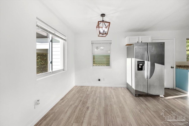 interior space featuring baseboards, a notable chandelier, and light wood finished floors