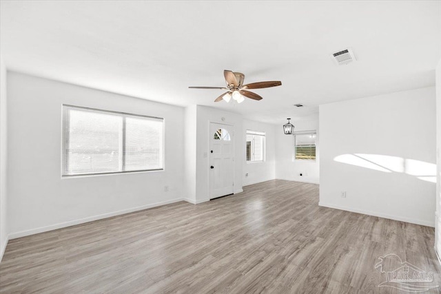 unfurnished living room with visible vents, plenty of natural light, ceiling fan, and wood finished floors