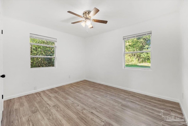 spare room with a wealth of natural light, a ceiling fan, light wood-type flooring, and baseboards