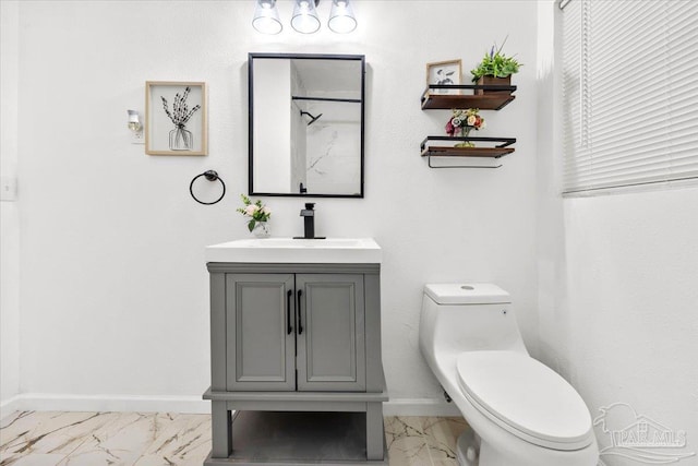 bathroom featuring marble finish floor, toilet, vanity, and baseboards