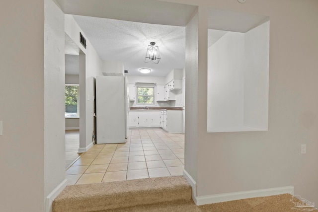 hallway with sink, light tile patterned floors, and a textured ceiling