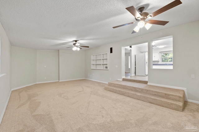 unfurnished living room featuring light carpet, ceiling fan, and a textured ceiling