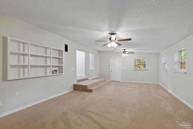 carpeted empty room featuring ceiling fan and a textured ceiling