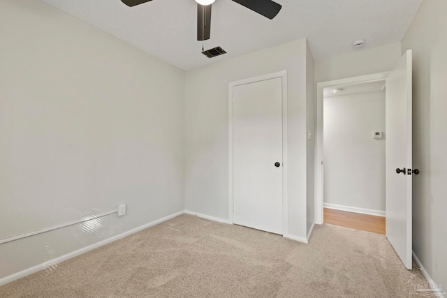 unfurnished bedroom with a closet, light carpet, and ceiling fan