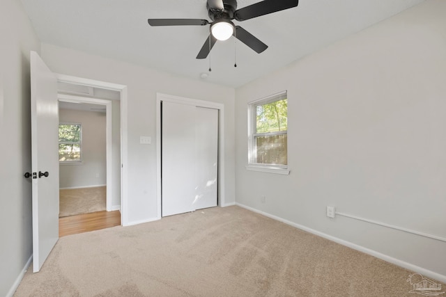 unfurnished bedroom featuring light carpet, multiple windows, and ceiling fan