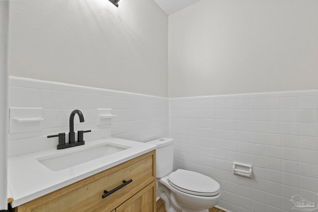 bathroom featuring vanity, tile walls, and toilet