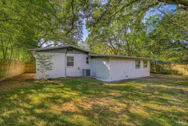 rear view of house featuring central AC and a lawn