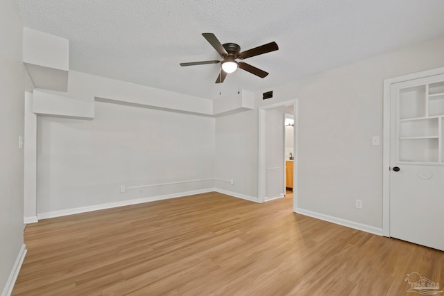 spare room featuring a textured ceiling, light wood-type flooring, and ceiling fan