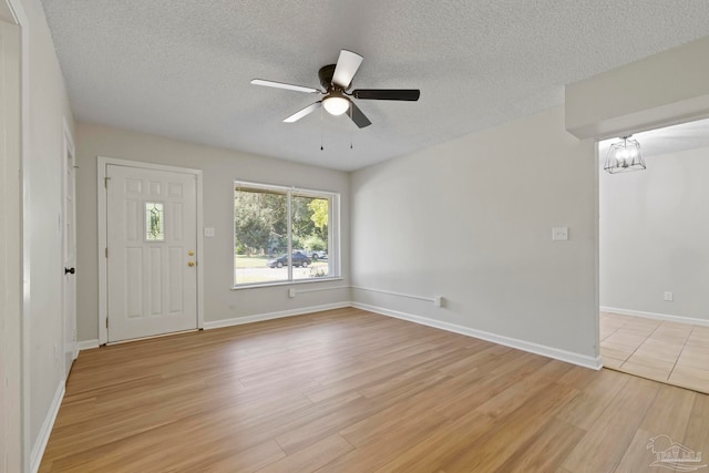 interior space with ceiling fan with notable chandelier, light hardwood / wood-style floors, and a textured ceiling