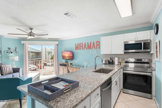 kitchen featuring visible vents, appliances with stainless steel finishes, a peninsula, crown molding, and a sink