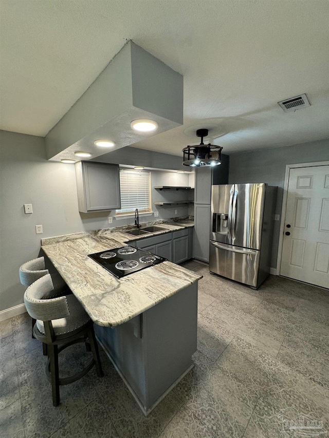 kitchen with black electric stovetop, gray cabinets, light countertops, a sink, and stainless steel fridge with ice dispenser