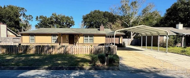 view of front of house featuring a fenced front yard, a chimney, stucco siding, a detached carport, and driveway