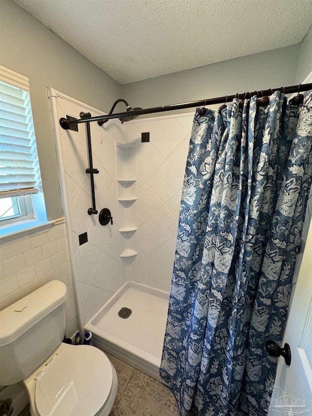 full bath with tile walls, toilet, a stall shower, a textured ceiling, and tile patterned floors