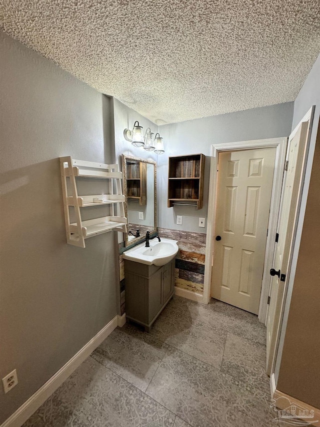 bathroom featuring baseboards, a textured ceiling, and vanity