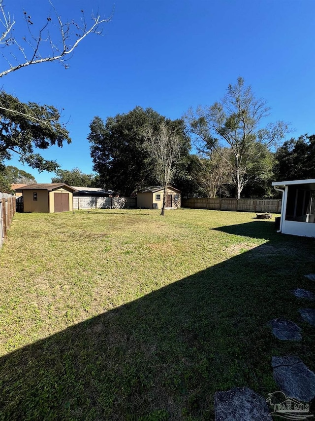 view of yard featuring a fenced backyard, a storage unit, and an outdoor structure