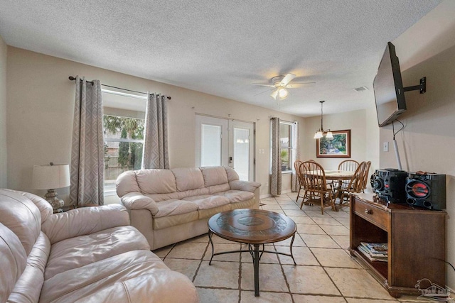 tiled living room featuring a textured ceiling, french doors, and ceiling fan