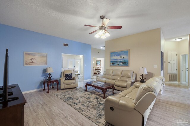 living room with light hardwood / wood-style floors, ceiling fan, and a textured ceiling