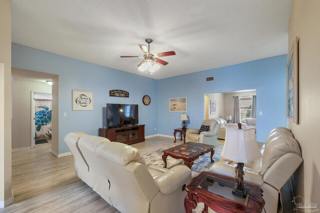 living room with a textured ceiling, ceiling fan, and light hardwood / wood-style floors