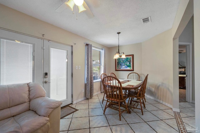 tiled dining space featuring a textured ceiling and ceiling fan