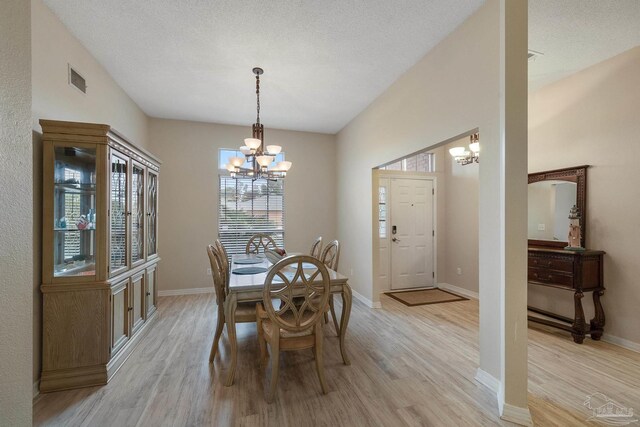 dining space featuring an inviting chandelier, a textured ceiling, and light hardwood / wood-style floors