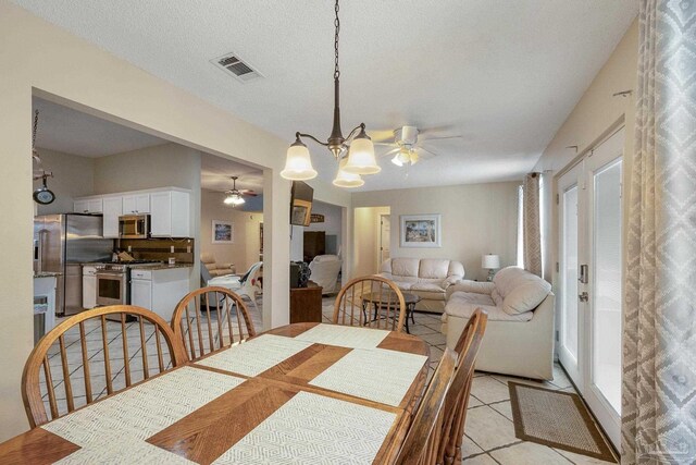 tiled dining area with a textured ceiling and ceiling fan