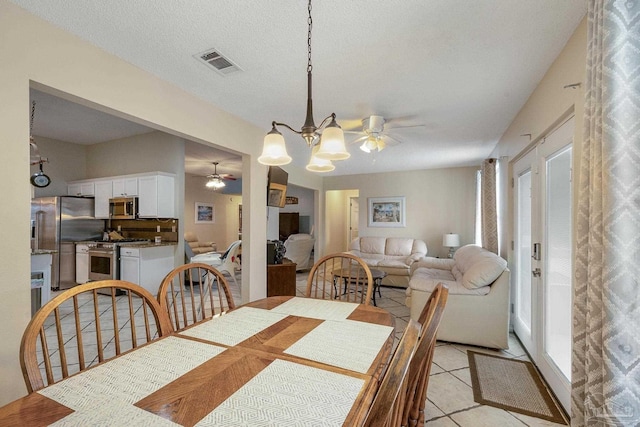 tiled dining area featuring ceiling fan with notable chandelier and a textured ceiling