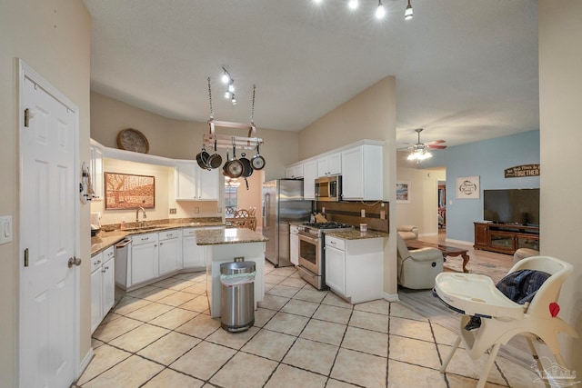 kitchen with white cabinets, a center island, light stone counters, ceiling fan, and stainless steel appliances