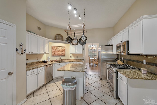 kitchen featuring appliances with stainless steel finishes, a kitchen island, sink, and white cabinetry