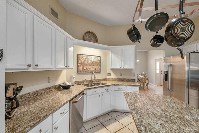 kitchen featuring light stone countertops, sink, light tile patterned floors, appliances with stainless steel finishes, and white cabinets