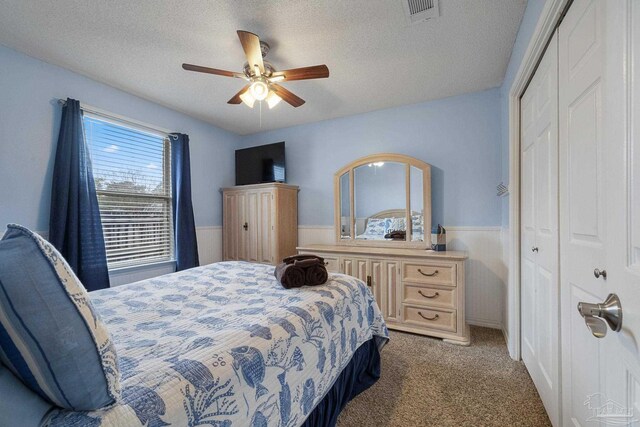 carpeted bedroom featuring a closet, a textured ceiling, and ceiling fan