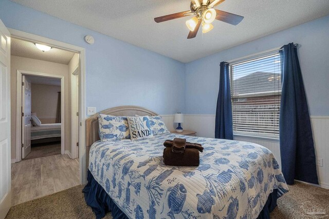 bedroom with light hardwood / wood-style floors, ceiling fan, and a textured ceiling