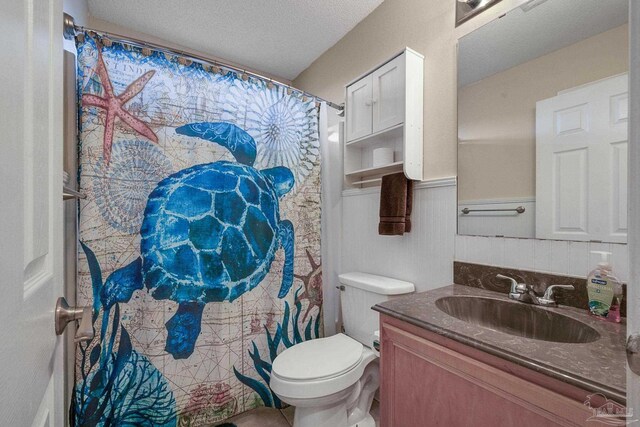 bathroom featuring vanity, toilet, tile patterned floors, and a textured ceiling