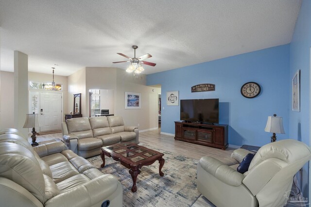 living room featuring light hardwood / wood-style flooring, a textured ceiling, and ceiling fan with notable chandelier