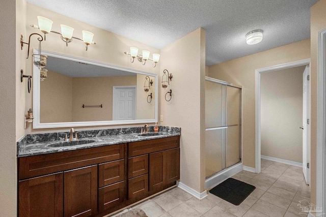 bathroom featuring dual vanity, a shower with door, a textured ceiling, and tile patterned floors