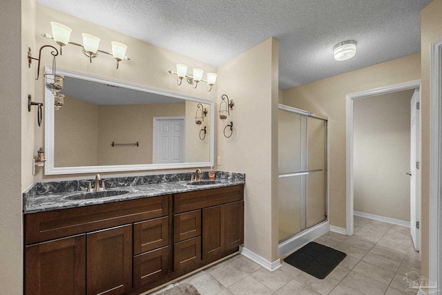 bathroom featuring a textured ceiling, vanity, walk in shower, and tile patterned floors