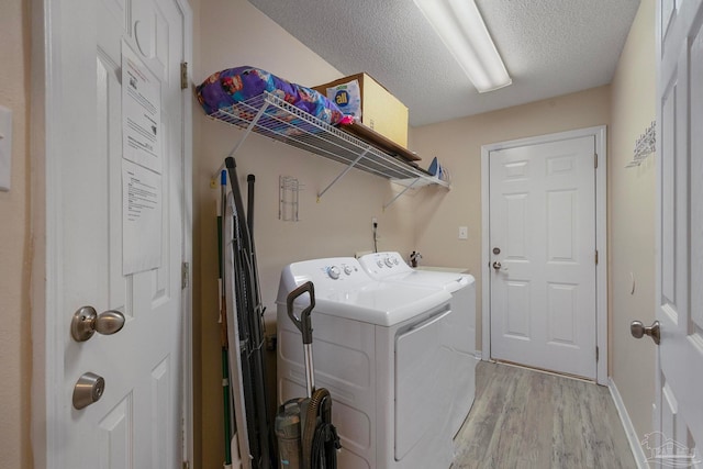 washroom with light hardwood / wood-style floors, separate washer and dryer, and a textured ceiling