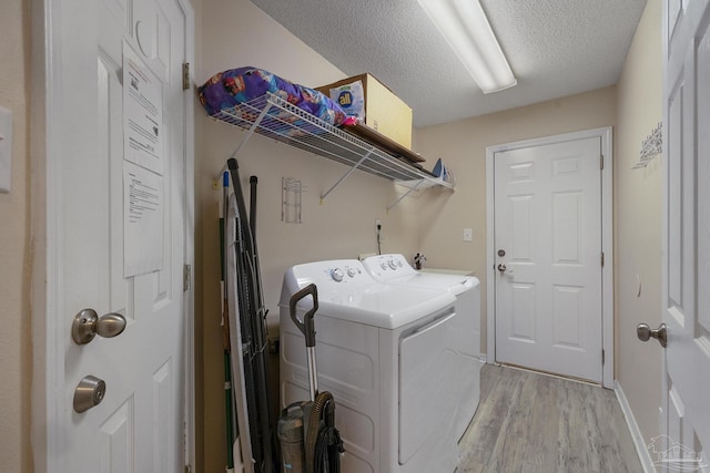 laundry area with a textured ceiling, light hardwood / wood-style floors, and washer and clothes dryer