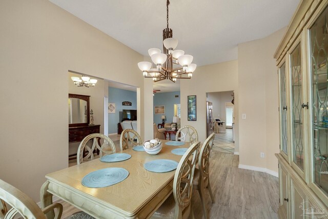 dining space with light hardwood / wood-style floors and a notable chandelier