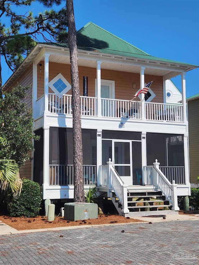 view of front facade with a sunroom, metal roof, and a balcony