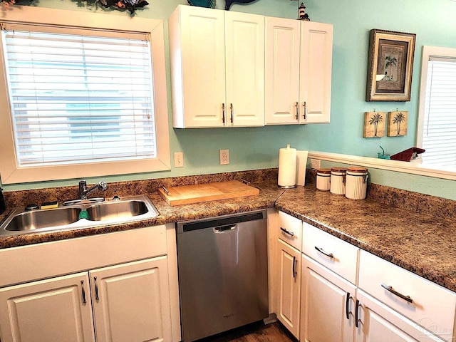 kitchen featuring dark countertops, white cabinets, dishwasher, and a sink