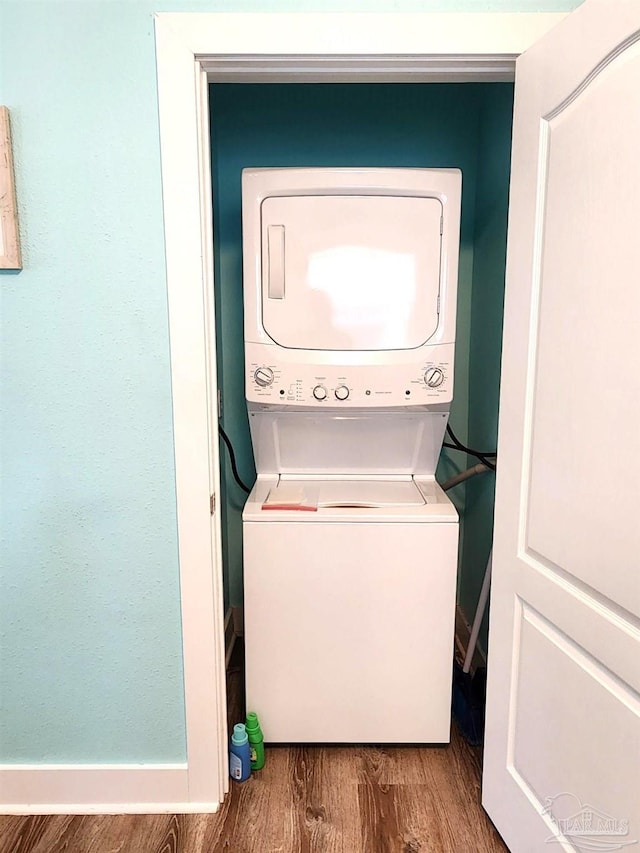 laundry area featuring laundry area, stacked washing maching and dryer, and wood finished floors