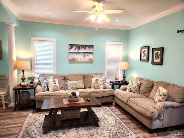 living area featuring wood finished floors, crown molding, ornate columns, and ceiling fan