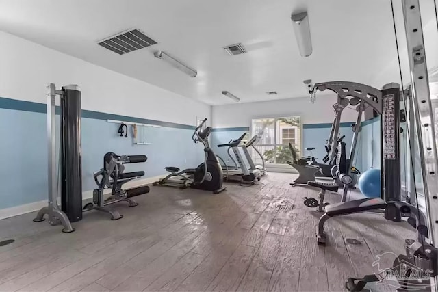 workout area featuring wood-type flooring, visible vents, and baseboards