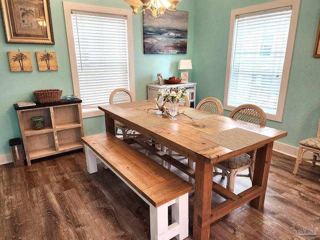 dining space featuring dark wood-style flooring, baseboards, and an inviting chandelier